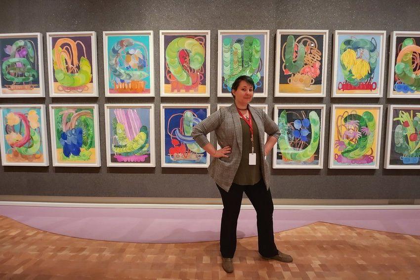 校友 Duffee Maddox posing in front of a gallery of hanging artwork